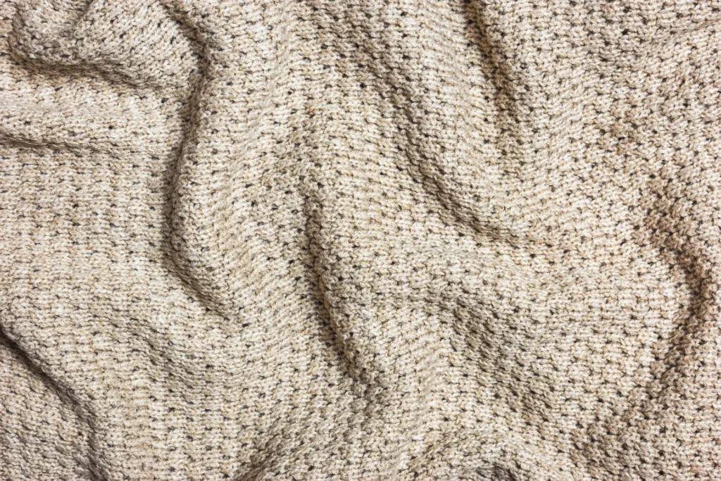 Teksturirana deka bež tkanine – detalj vunenog pokrivača